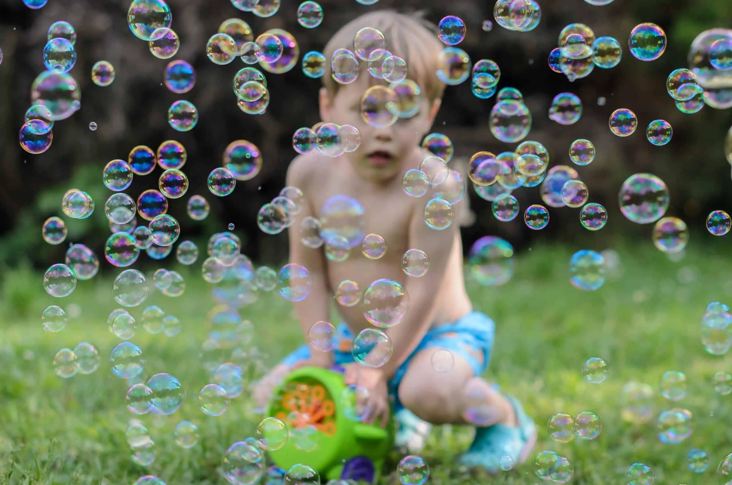 Blure boy plays with soap bubbles maker machine in the courtyard